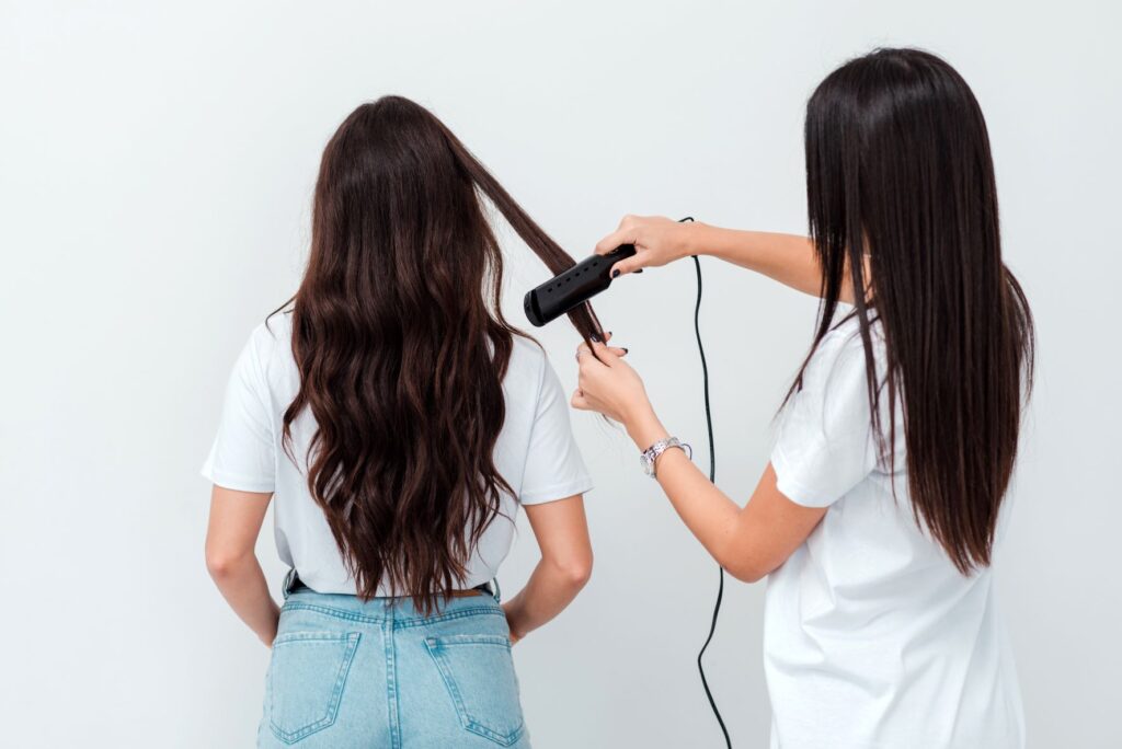 Professional hairdresser straightens the clients