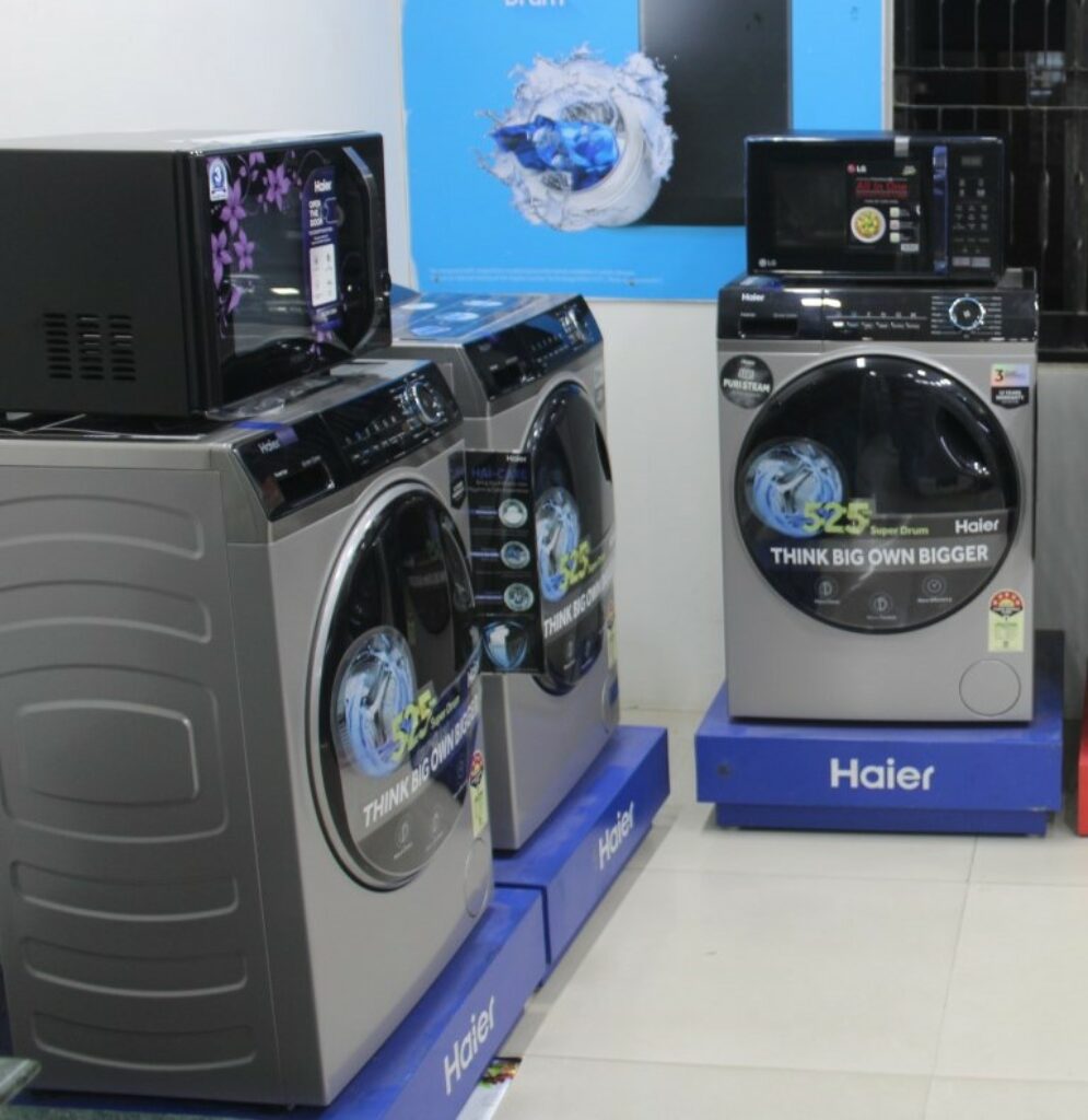 There are three Haier 8 Kg 5 Star Inverter Motor Fully Automatic Front Load Washing Machine image captured in a store