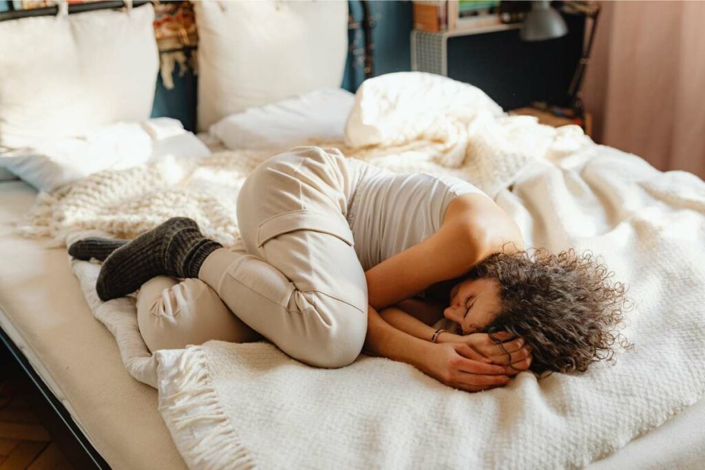 A woman sleeping uncomfortably on a bed, struggling with the discomfort caused by the mattress.
