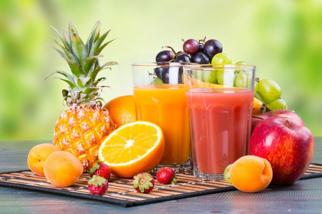 A mouth-watering display of fresh fruit and a glass of fruit juice on a wooden table, ideal for a nutritious and tasty start to the day