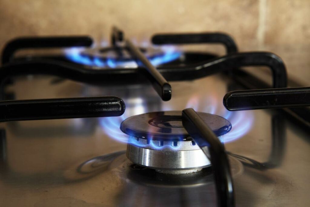 A gas stove emitting blue flames, showcasing its hot surfaces