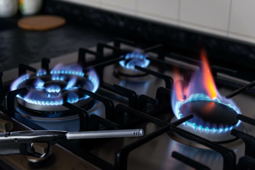 A gas stove ablaze with vibrant blue flames, ignited by a lighter