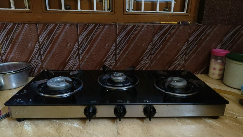 Three-burner gas stove with visible scratch mark on the surface