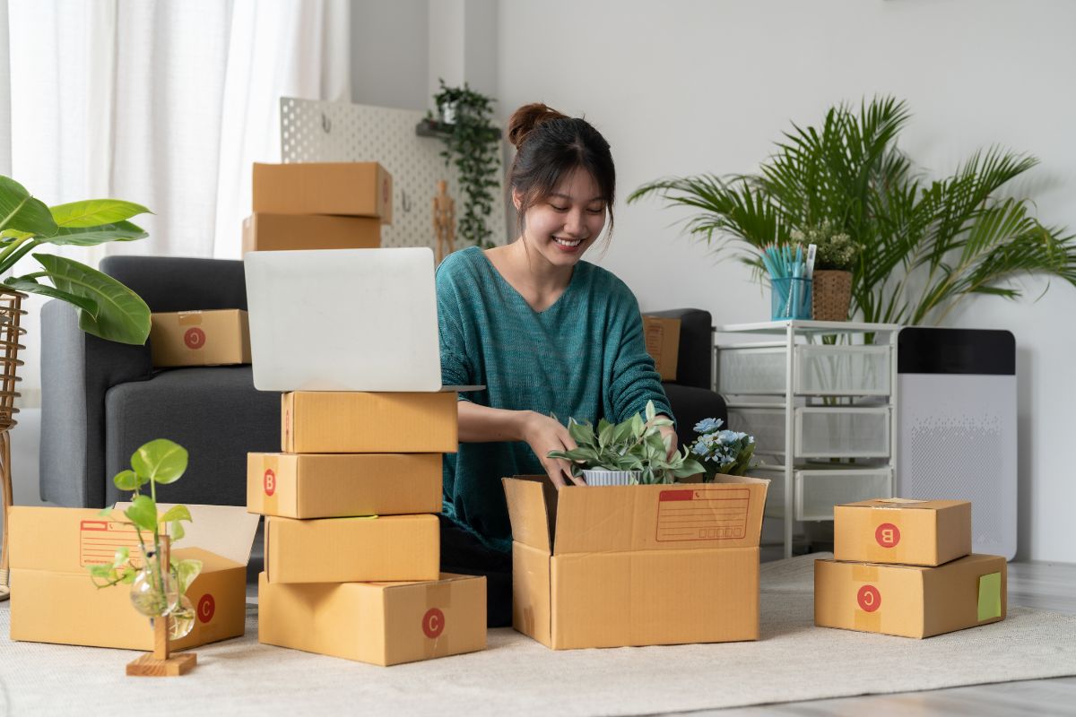 A woman carefully packing a sapling for delivery as part of an online sale.