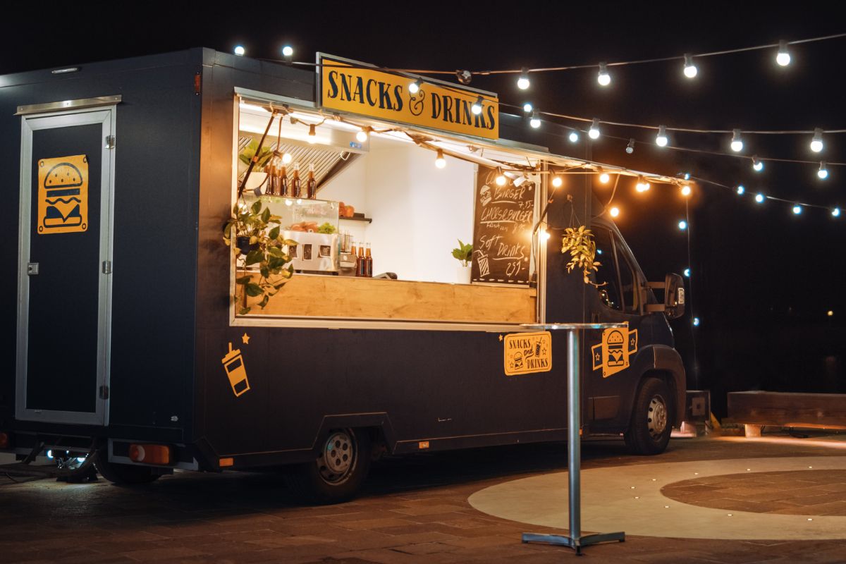 A food truck parked at night, illuminated by bright lights