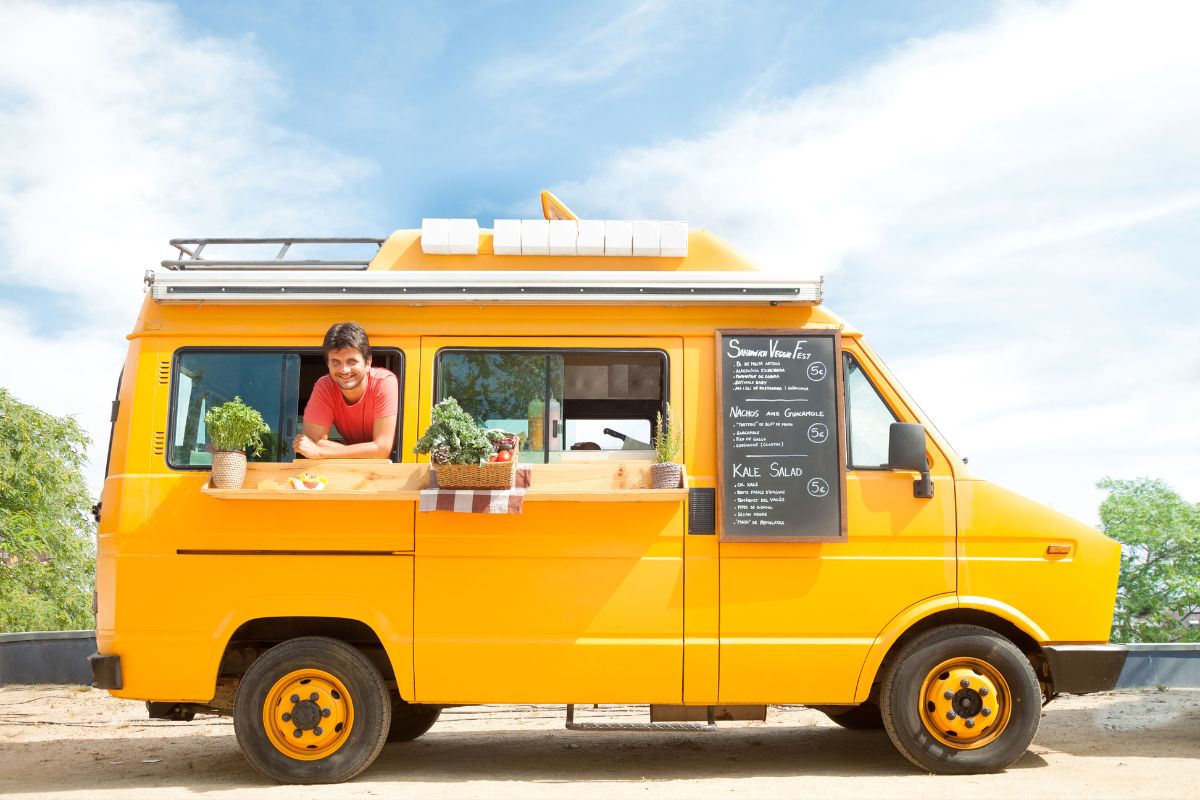 A man stands in front of a food truck, serving delicious meals from a vibrant and inviting mobile kitchen.